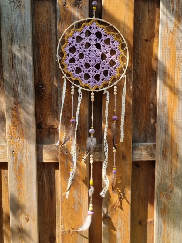 Détail des franges en tissu insérées entre les perles en bois et les plumes