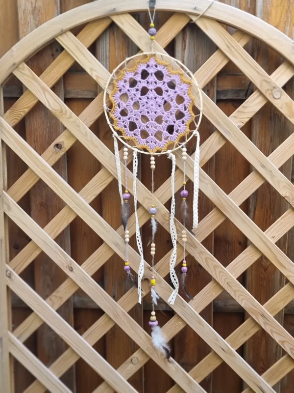 Vue des franges en tissu insérées entre les perles en bois et les plumes