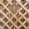 Attrape-rêves motif soleil en raffia avec centre jaune sur cerclage en acier vert, perles en céramique et plumes