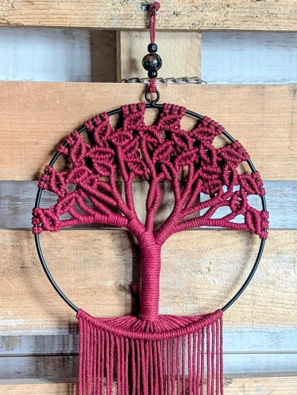 Détail suspension murale macramé arbre rouge sur cercle avec franges retombantes